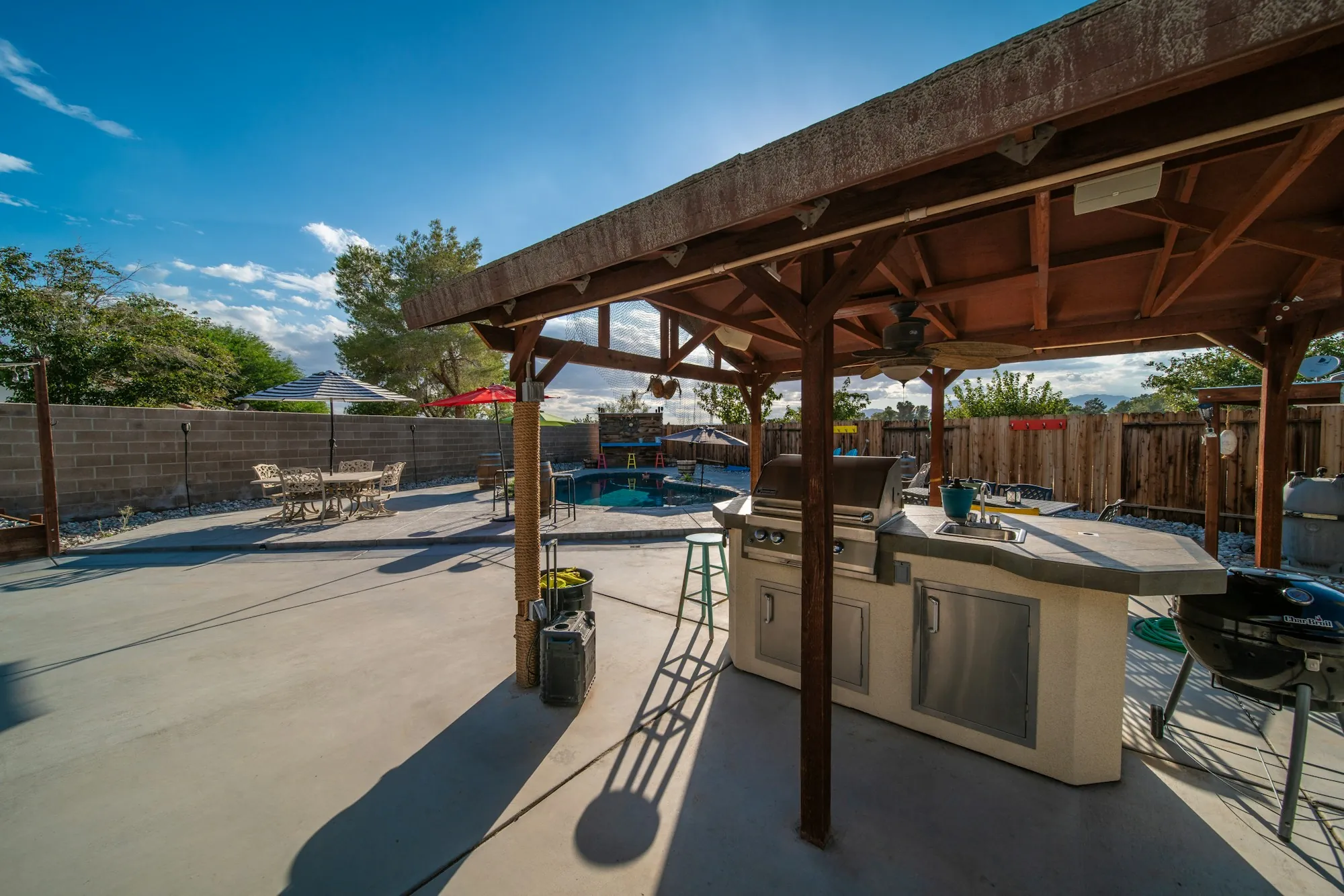 Concrete patio with an outdoor kitchen under a wood pavilion