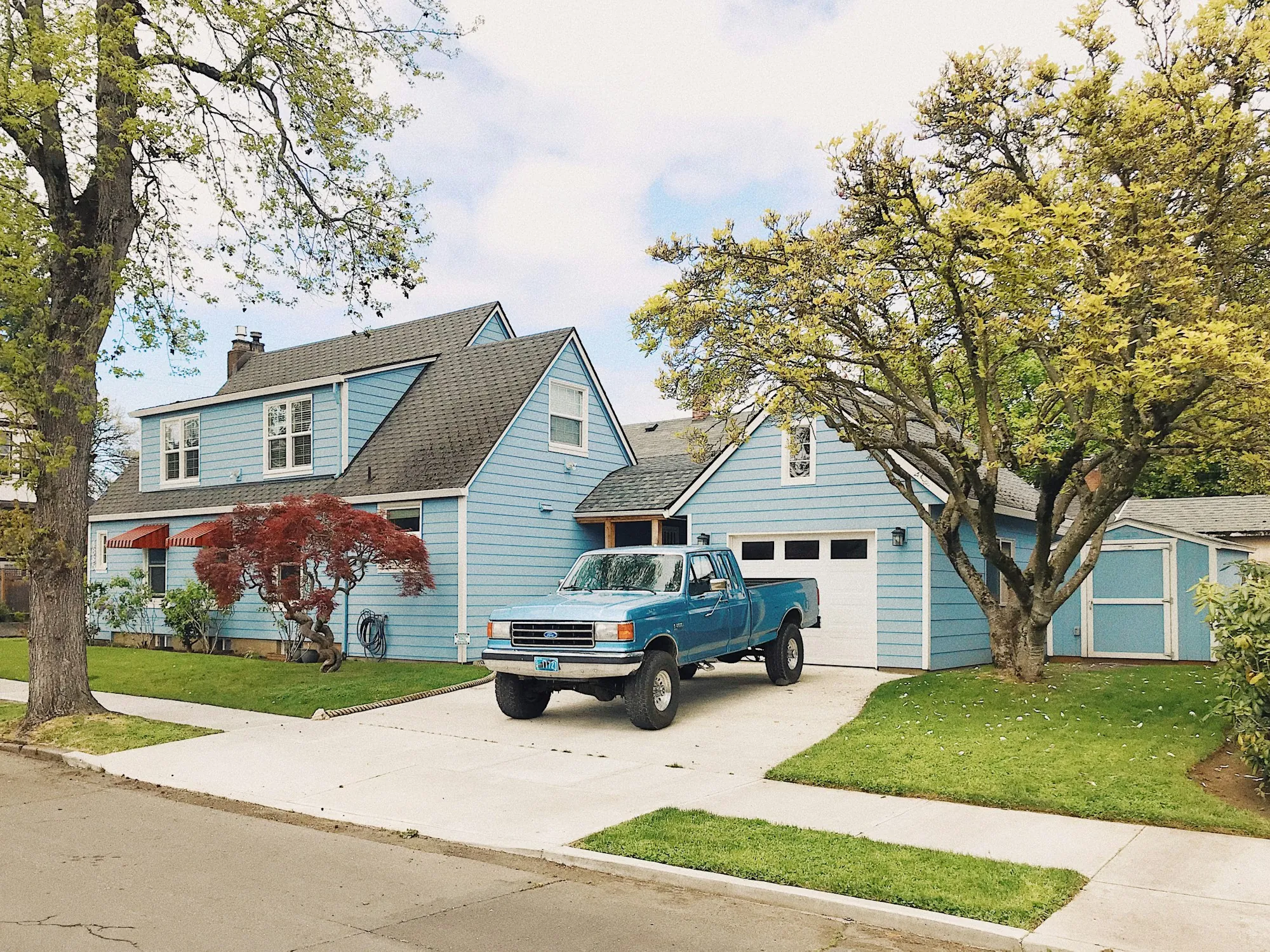 Blue house with a pickup truck in a concrete driveway