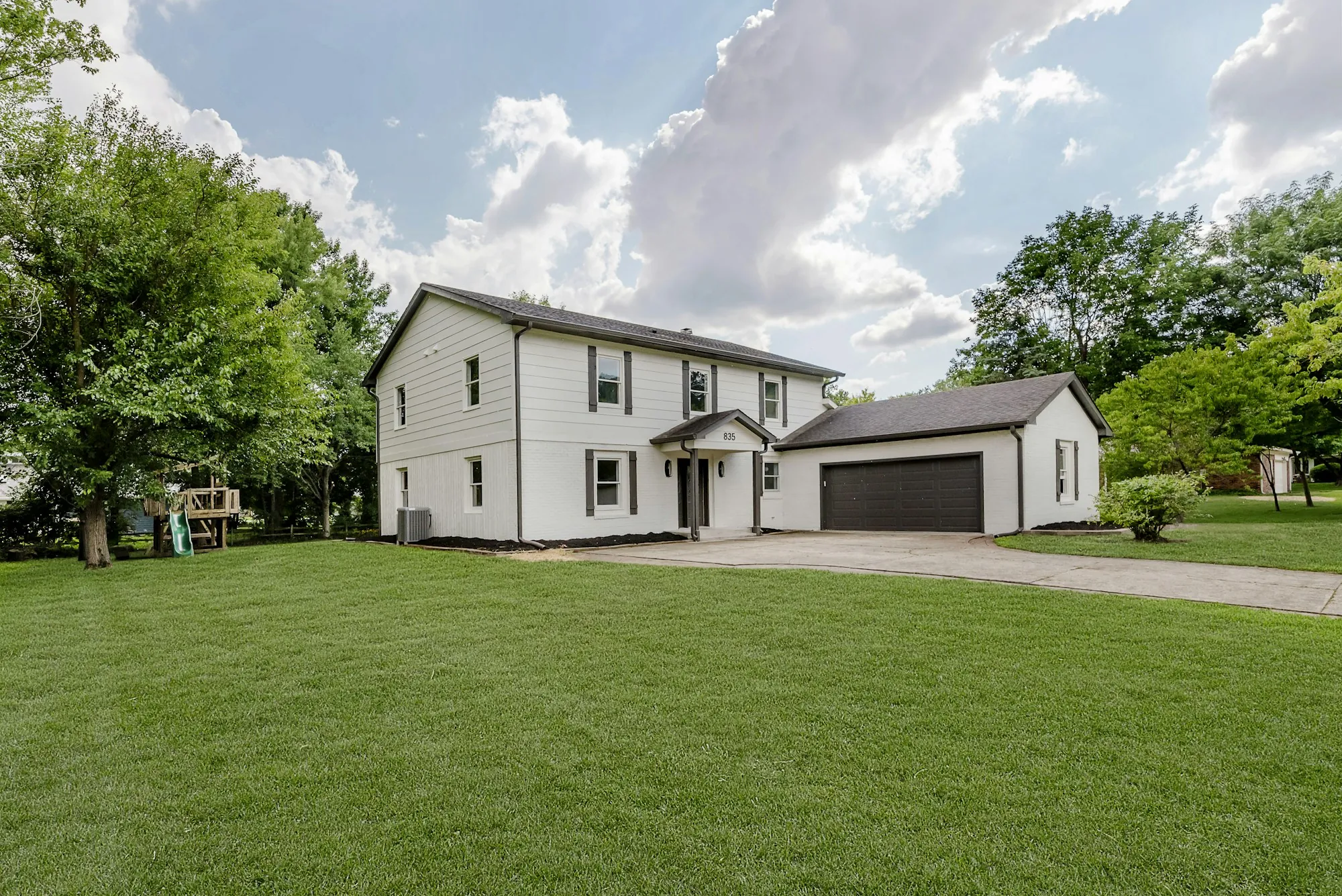 White farmhouse with a detached garage and wide lawn